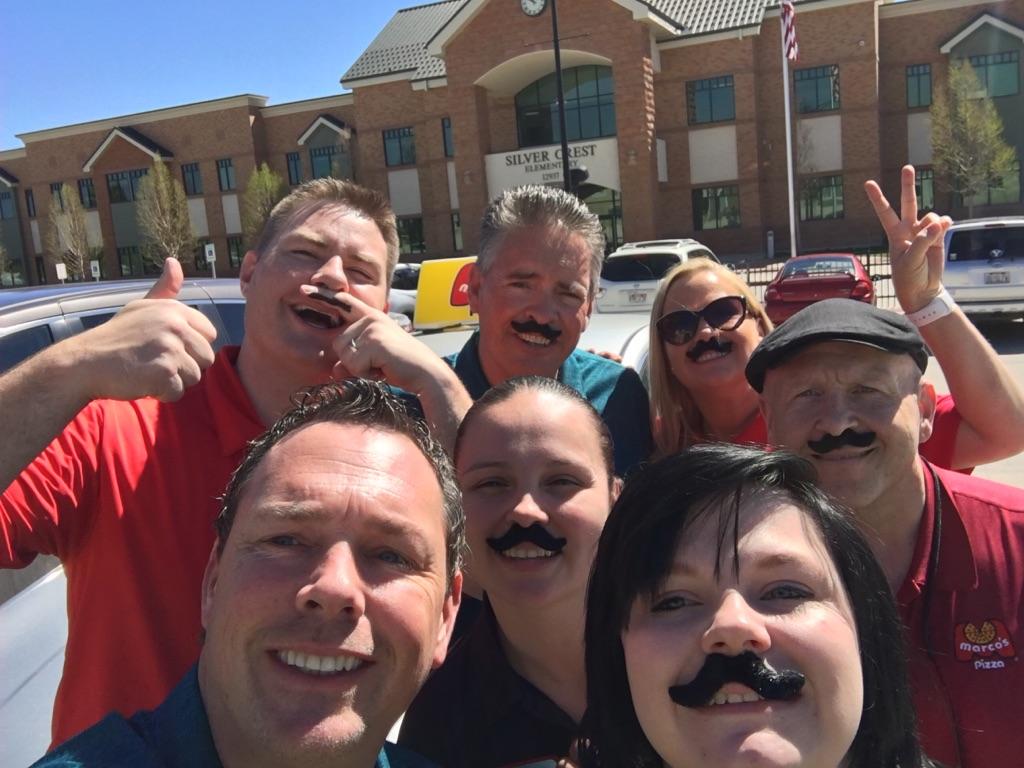 Marco's Pizza crew in mustaches outside Silver Crest Elementary School