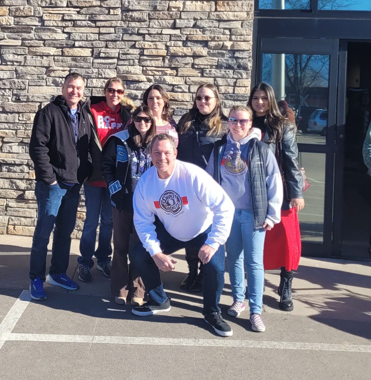 Shipley Do-Nuts crew posing in front of a local school building